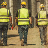 Construction workers in safety gear walking away from camera
