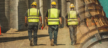 Construction workers in safety gear walking away from camera